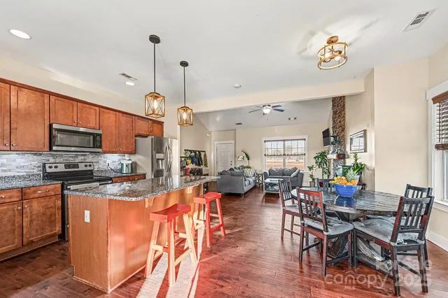 a view of a dining room and livingroom with furniture wooden floor a rug a flat screen tv a rug and a chandelier