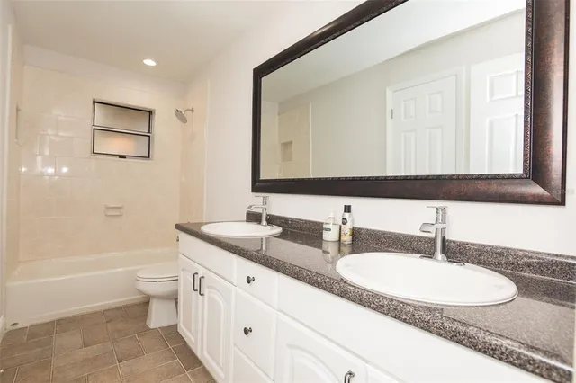 a bathroom with a granite countertop sink a toilet a mirror and bathtub
