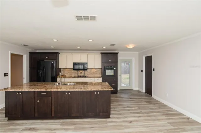 a large kitchen with stainless steel appliances granite countertop a large counter top and a wooden floors