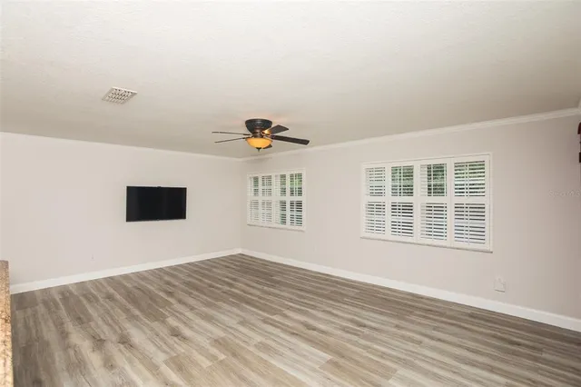 a view of an empty room with a window and wooden floor