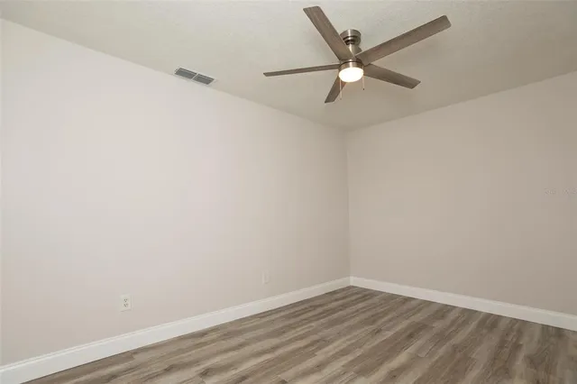 an empty room with wooden floor and ceiling fan