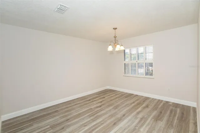 an empty room with wooden floor and chandelier