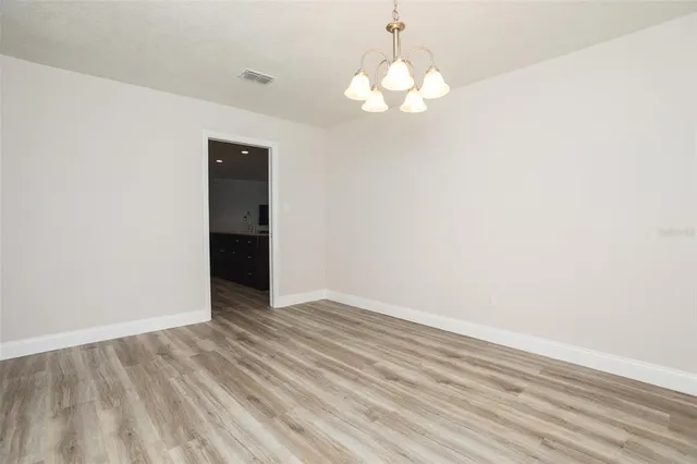 an empty room with wooden floor and chandelier