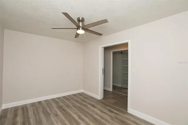 an empty room with wooden floor fan and windows