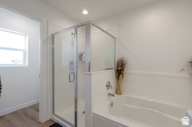 8254 Cascade Vw Way Magna, UT 84044 - Photo 11 of 12 Enclosed shower with clear glass door, built-in bathtub, recessed ceiling lighting, and wood-finish flooring