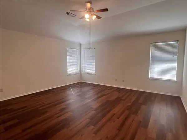a view of empty room with wooden floor and fan