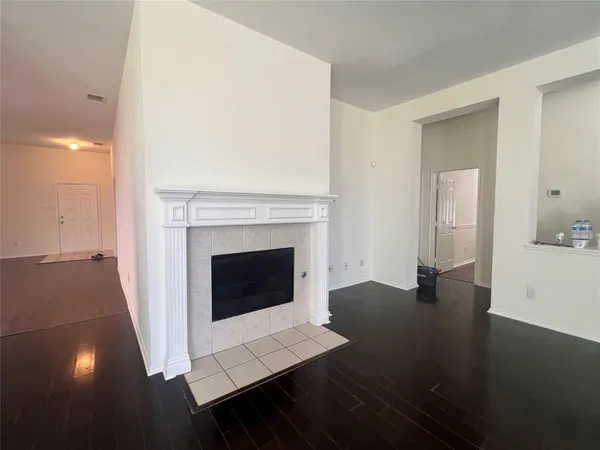 a view of an empty room with wooden floor and a fireplace