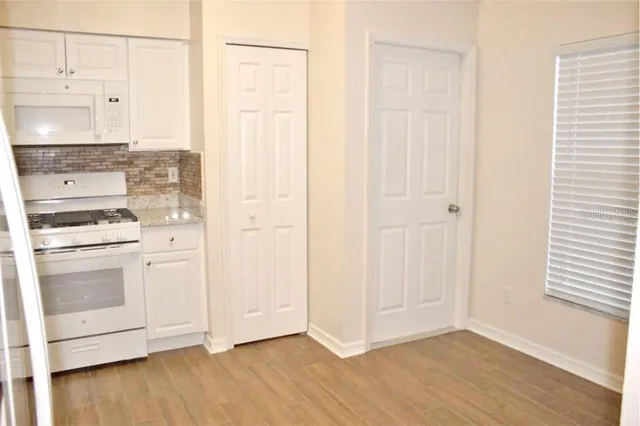 a view of a kitchen with white cabinets and wooden floor
