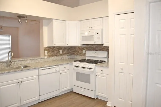 a kitchen with white cabinets and white appliances