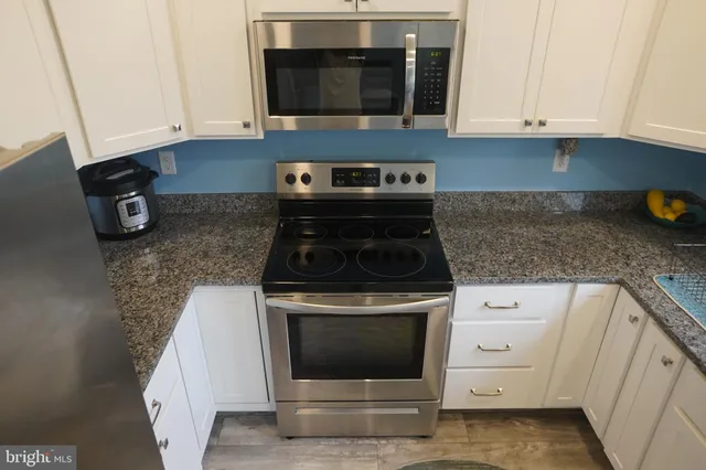 a kitchen with granite countertop white cabinets and stainless steel appliances