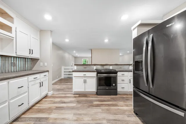 a kitchen with granite countertop a refrigerator stove top oven and sink