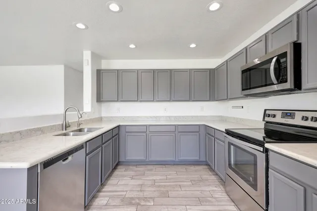 a kitchen with stainless steel appliances granite countertop a sink and dishwasher a stove top oven with wooden floor
