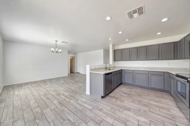 a large kitchen with a sink and dishwasher a stove with wooden floors