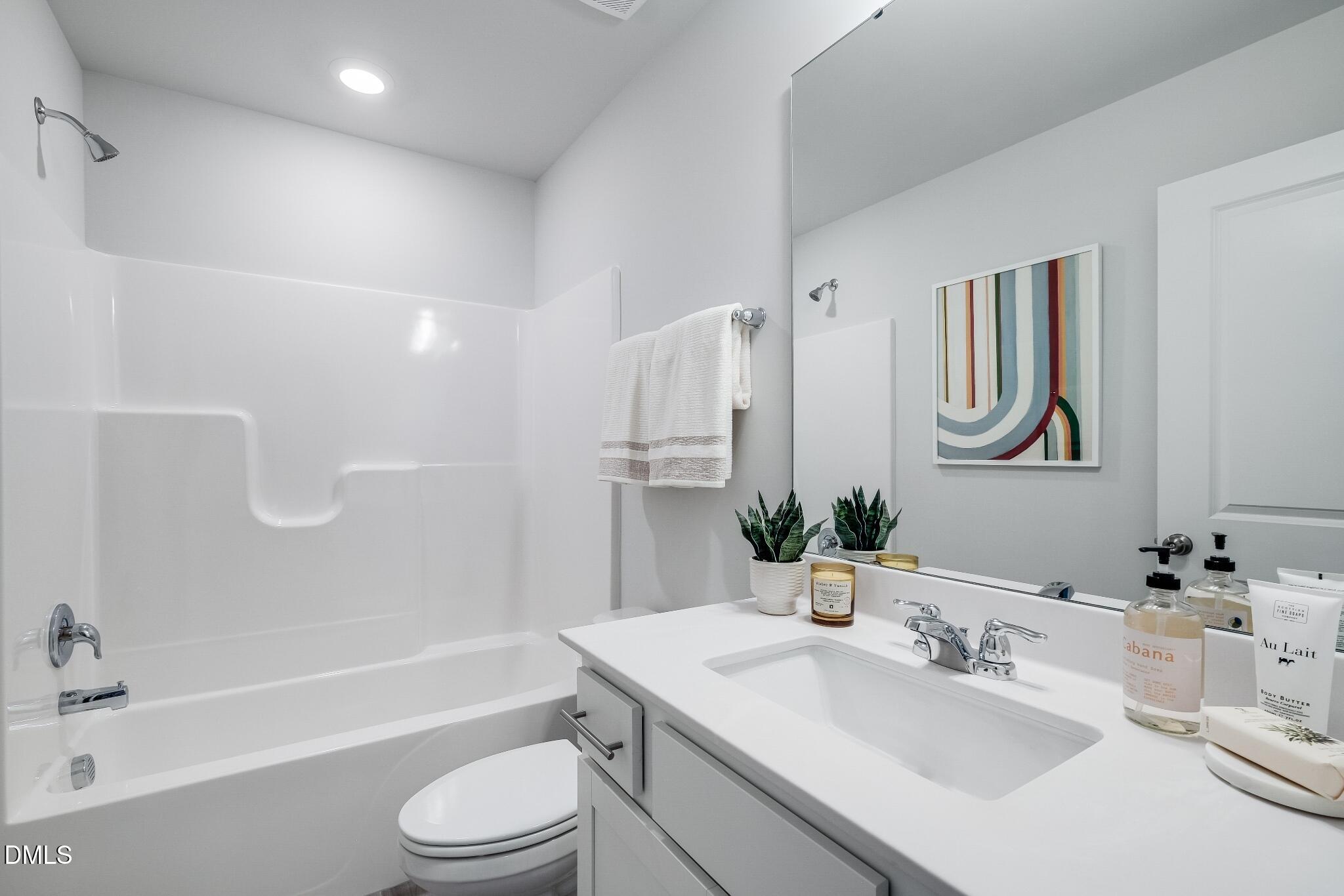 1028 Red Finch Way Angier, NC 27501 - Photo 31 of 40 a bathroom with a toilet a sink a mirror a bathtub and shower