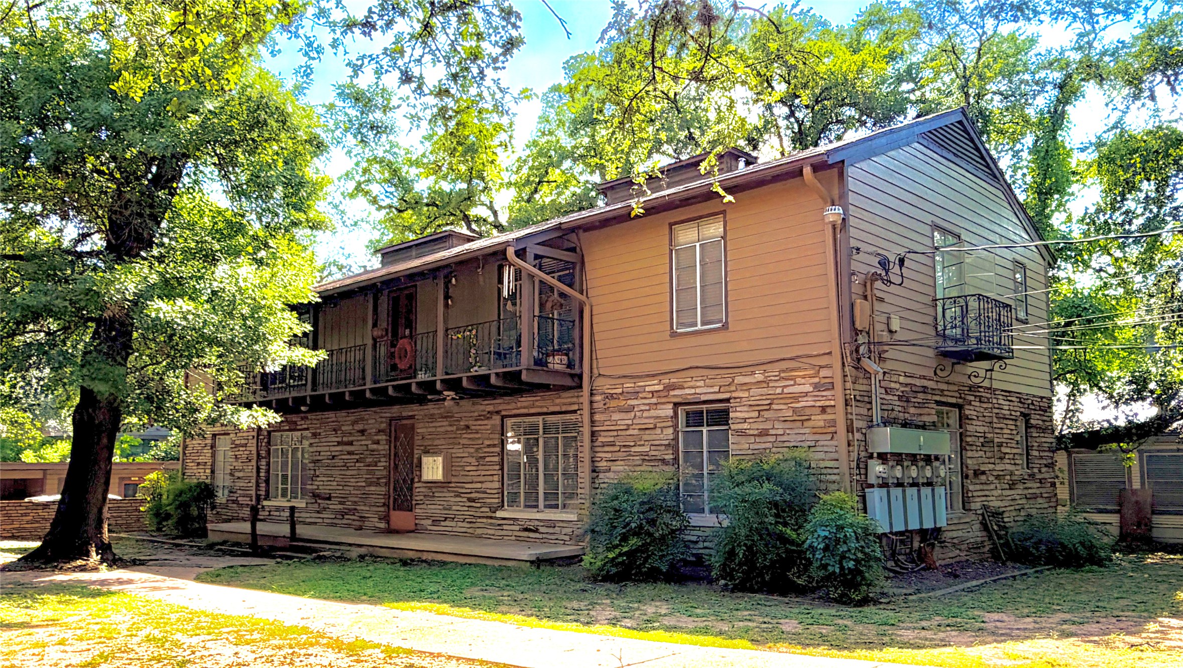 Stone and siding exterior featuring multiple windows and a second-story balcony with metal railings