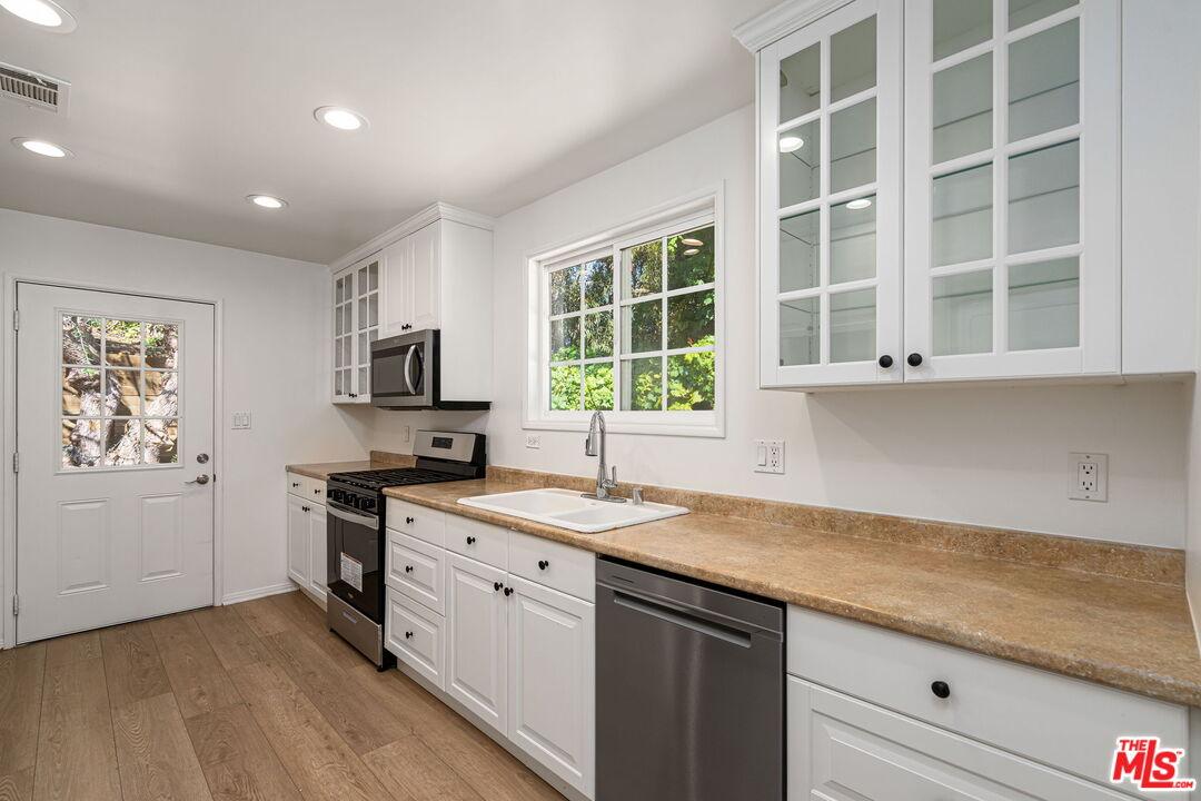 3919 South Ridgeley Drive Los Angeles, CA 90008 - Photo 11 of 23 a kitchen with a sink stove and cabinets