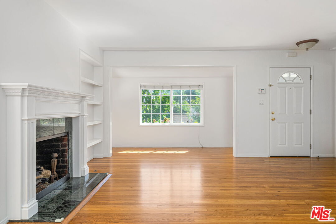 3919 South Ridgeley Drive Los Angeles, CA 90008 - Photo 8 of 23 a view of an empty room with wooden floor fireplace and a window