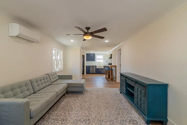 a living room with couches and kitchen view with wooden floor