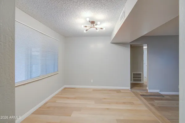 a view of an empty room with chandelier fan and window