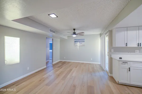 an empty room with wooden floor cabinet and windows