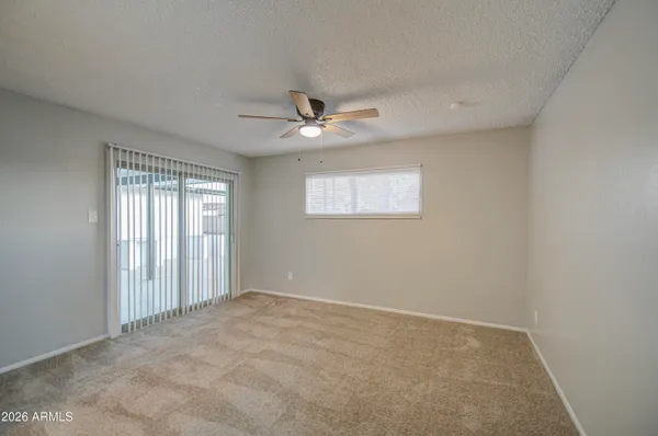 an empty room with windows and ceiling fan