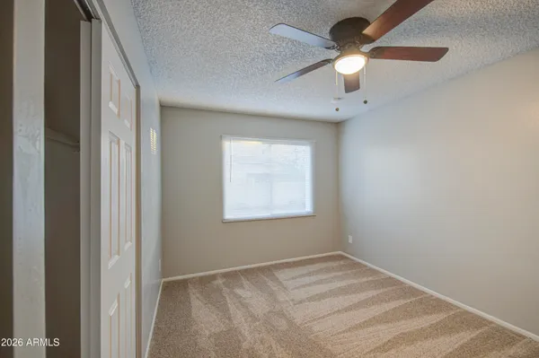 an empty room with a window and a fan