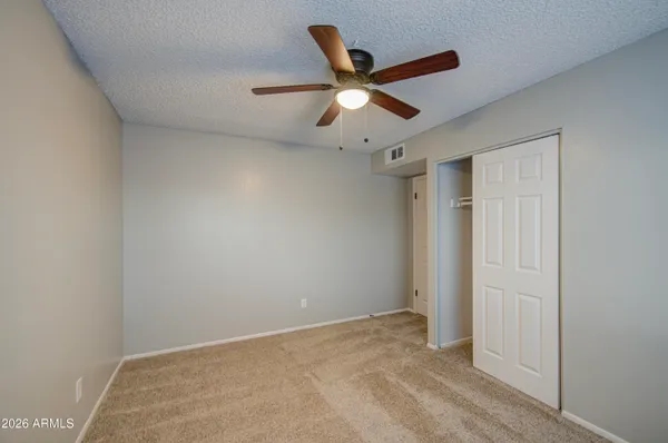 an empty room with closet and a ceiling fan
