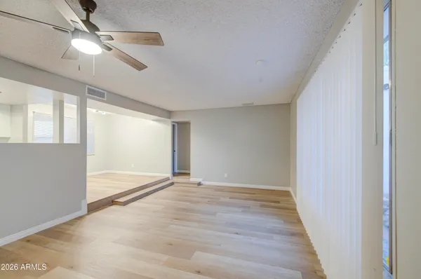 a view of an empty room with wooden floor and a window