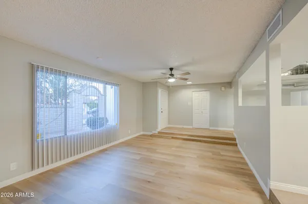 a view of empty room with wooden floor and fan