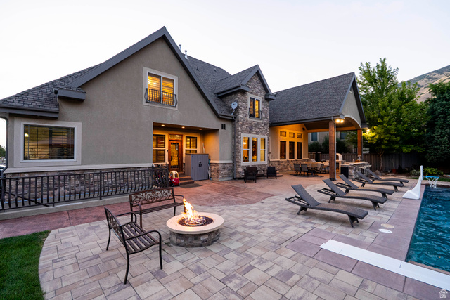 687 South 2080th Street East Springville, UT 84663 - Photo 133 of 149 Rear exterior featuring stucco and stone veneer, a covered patio with an outdoor kitchen, a paver patio with a built-in fire pit, and an in-ground swimming pool