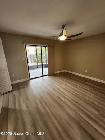 an empty room with wooden floor fan and windows