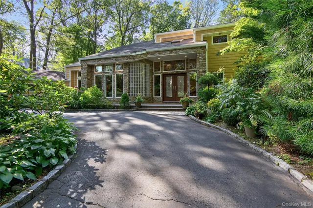 a view of brick house with potted plants and large trees