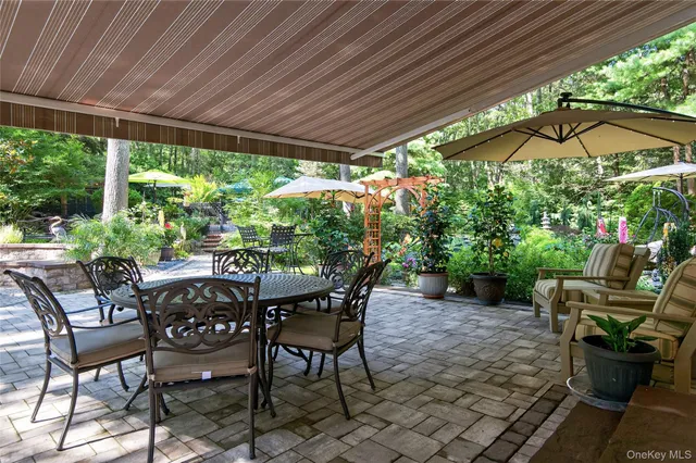 a view of patio with table and chairs under an umbrella with a small yard