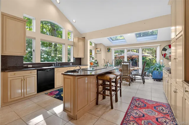 a open kitchen with stainless steel appliances granite countertop a refrigerator a sink a stove and white cabinets with wooden floor