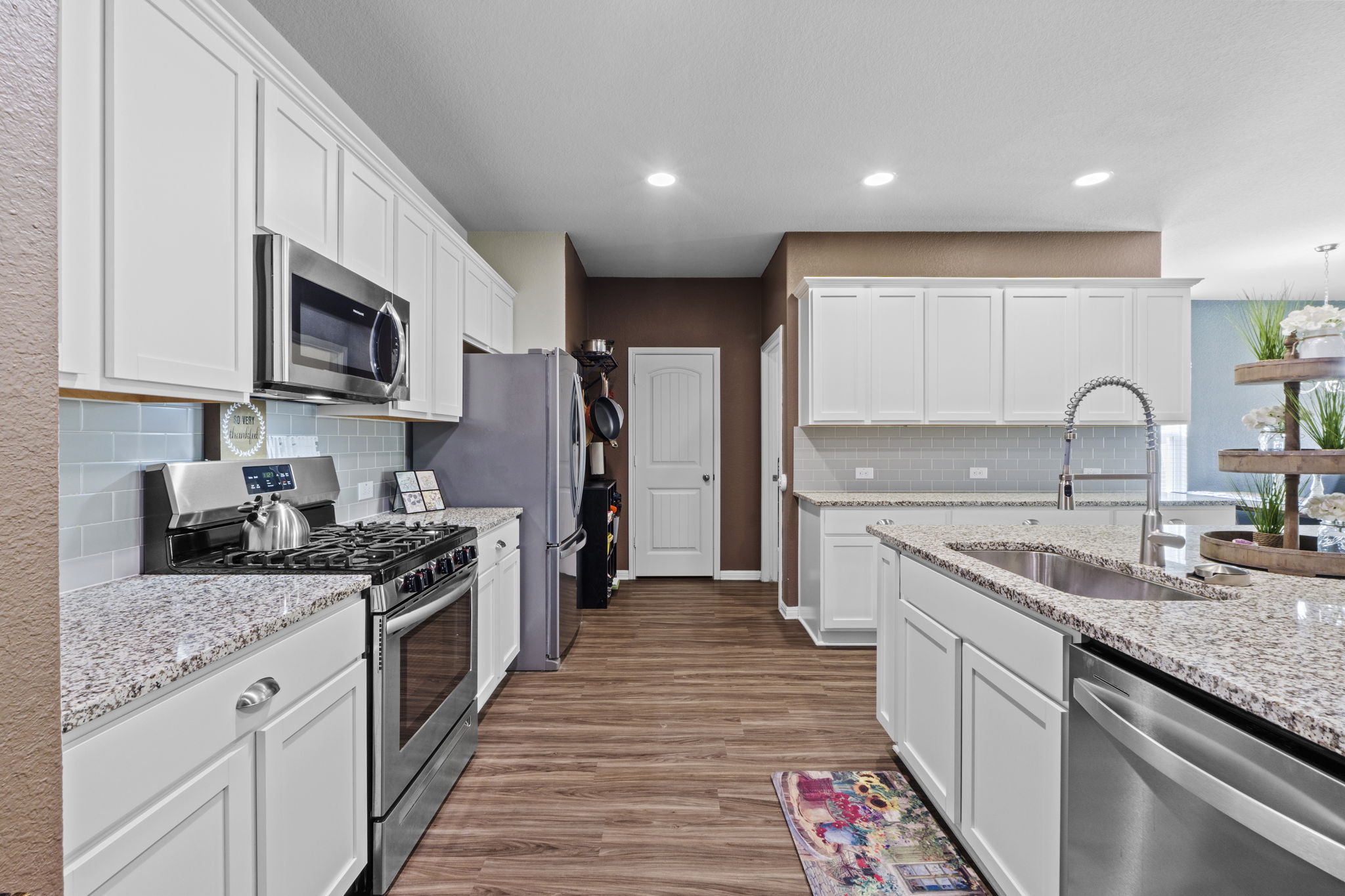 2417 Bridges Ranch Road Georgetown, TX 78628 - Photo 23 of 36 Kitchen with stainless steel appliances, white cabinetry, dark wood-type flooring, recessed lighting, and light stone countertops