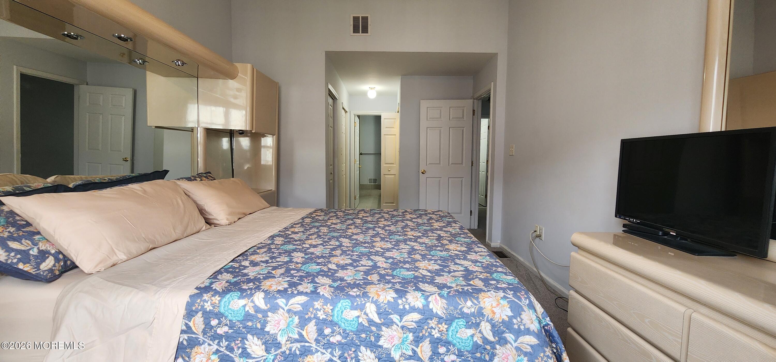 117 Mid Ocean Court, Unit 1000 Howell, NJ 07731 - Photo 16 of 24 a bedroom with a bed and a flat tv screen on a dresser
