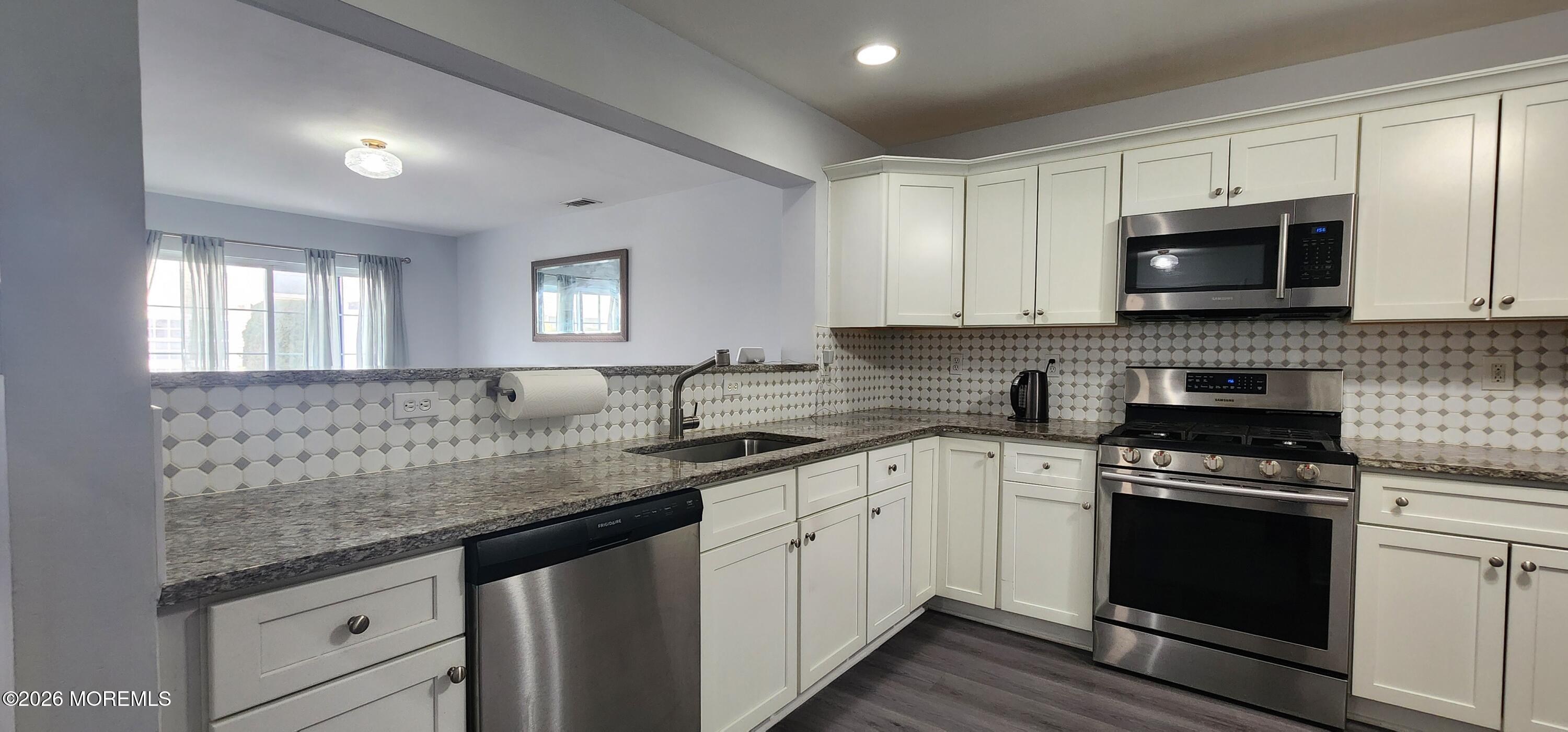 117 Mid Ocean Court, Unit 1000 Howell, NJ 07731 - Photo 6 of 24 a kitchen with granite countertop a sink a stove and cabinets