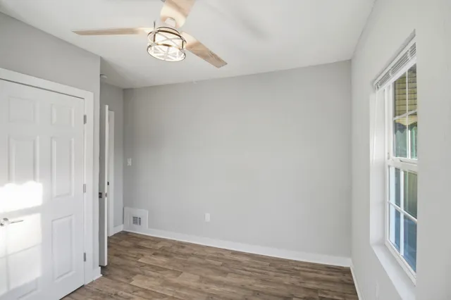 a view of an empty room with wooden floor and a window