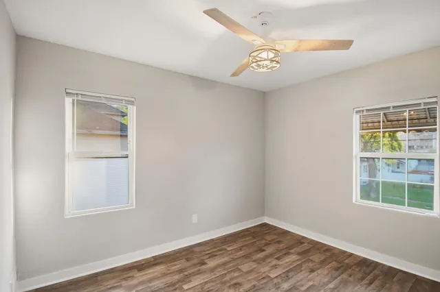 a view of an empty room with a window and wooden floor