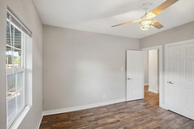 a view of an empty room with wooden floor and a window
