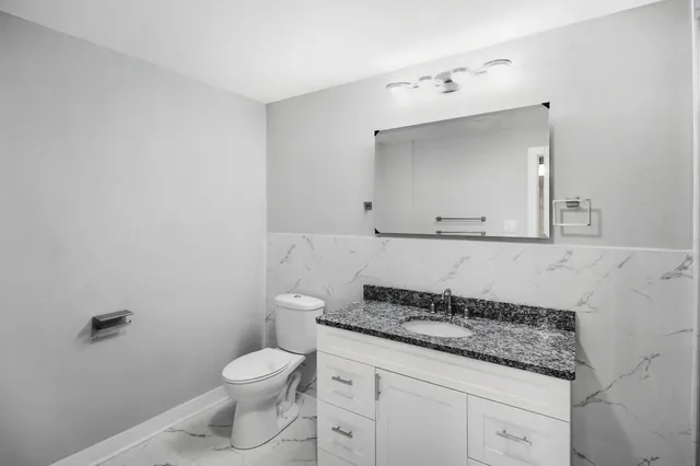 a bathroom with a granite countertop sink a toilet and a mirror