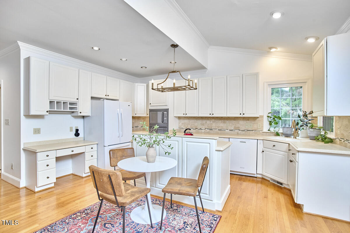 8605 Stanton Place Raleigh, NC 27615 - Photo 20 of 56 a kitchen with a dining table chairs wooden floor cabinets and appliances