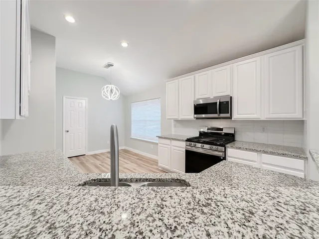 a kitchen with granite countertop a stove sink and microwave