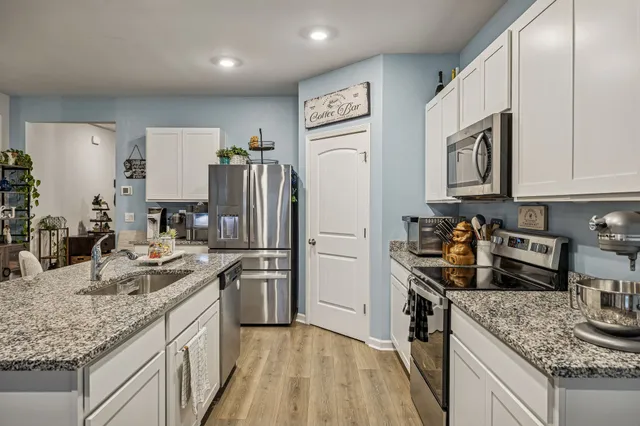 a kitchen with stainless steel appliances granite countertop a sink refrigerator and cabinets