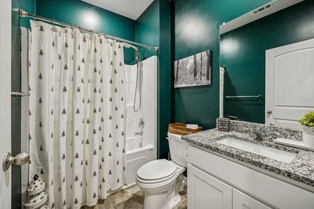 a bathroom with a granite countertop sink toilet and shower
