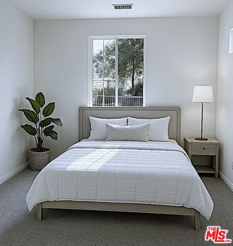 a bedroom with a bed lamp and a potted plant