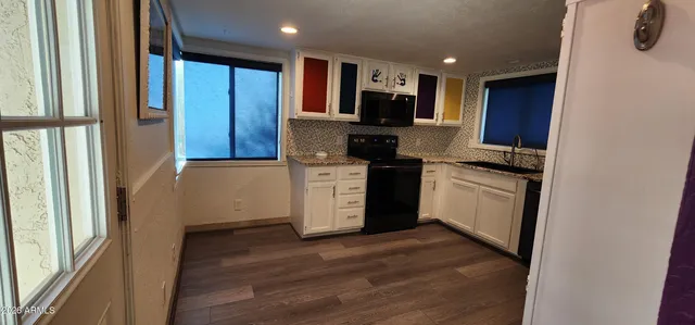 a kitchen with stainless steel appliances granite countertop a stove top oven a sink and a refrigerator with wooden floor