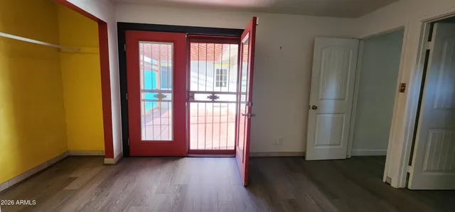 an empty room with wooden floor and windows with curtains