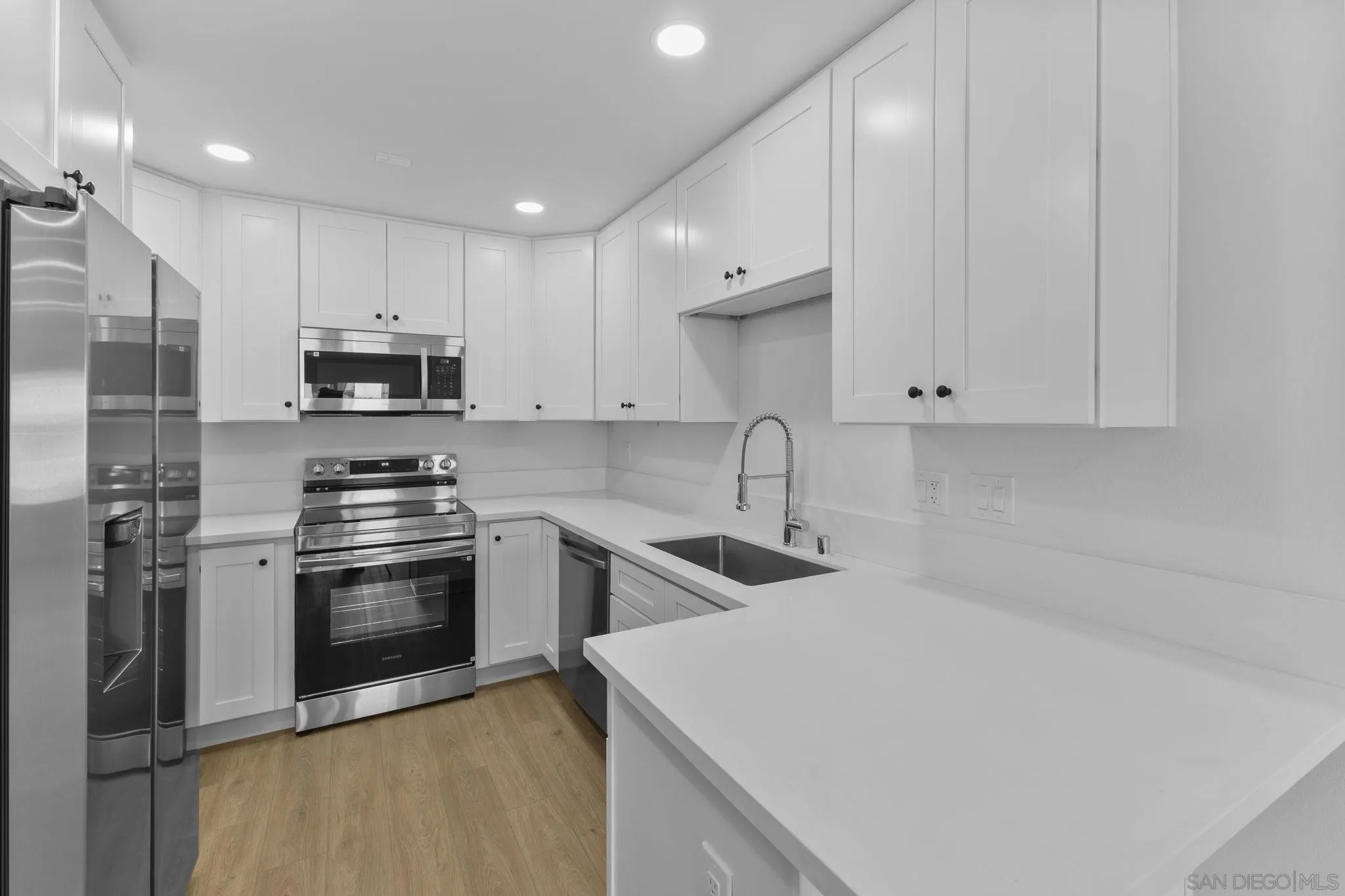 6747 Friars Road, Unit 130 San Diego, CA 92108 - Photo 3 of 32 a kitchen with stainless steel appliances a sink a stove a microwave and white cabinets