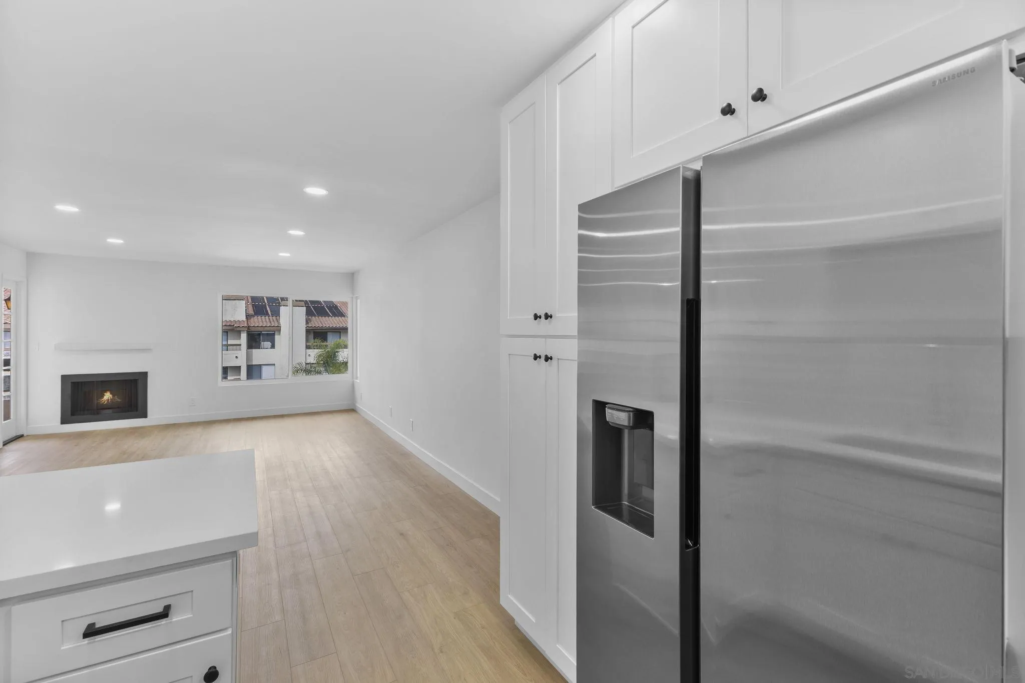 6747 Friars Road, Unit 130 San Diego, CA 92108 - Photo 5 of 32 a view of a refrigerator in kitchen and an empty room with wooden floor